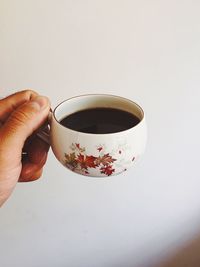 Hand holding tea cup against clear sky