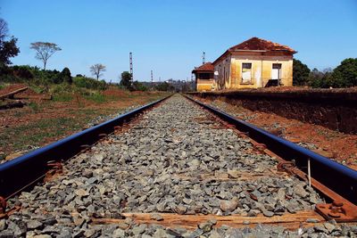 Surface level of railroad track passing by houses against clear sky