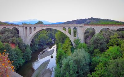 Arch bridge over river against clear sky