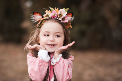 Cute smiling kid girl 3-4 year old wearing floral hairband outdoors. spring season.