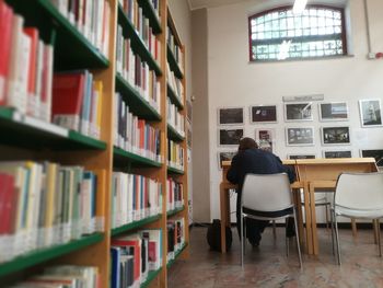 Rear view of man reading book in library