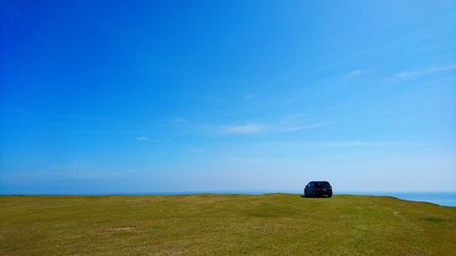 Car on field against blue sky