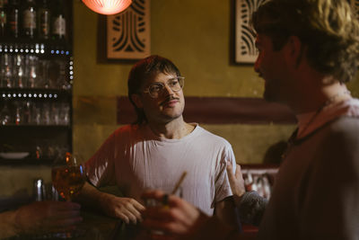 Smiling gay man listening to boyfriend near counter at bar