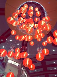 Low angle view of illuminated lanterns hanging against orange sky