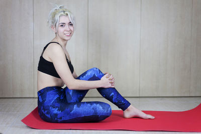 Portrait of woman sitting on exercise mat at health club