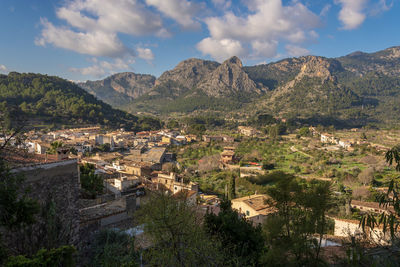 Aerial view of townscape by mountain against sky