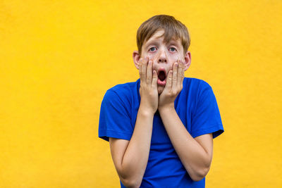 Portrait of teenage boy against yellow wall