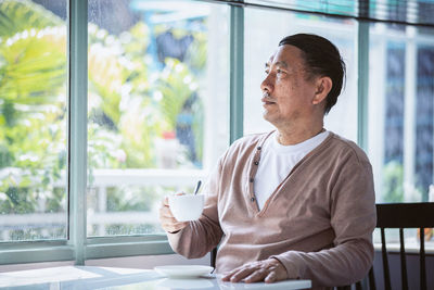 Man looking away while holding glass window