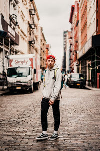 Full length portrait of young man standing on city street