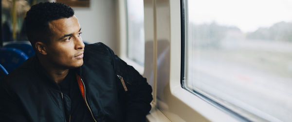 Man injecting insulin while sitting by window in train