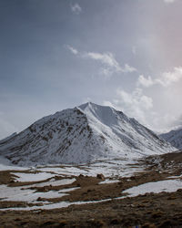 Scenic view of snowcapped mountains against cloudy sky