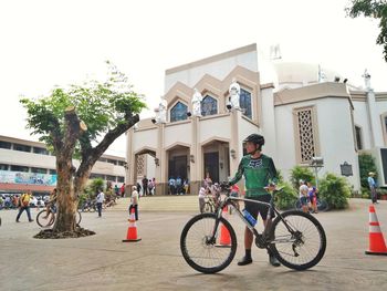 Man riding bicycle against building in city