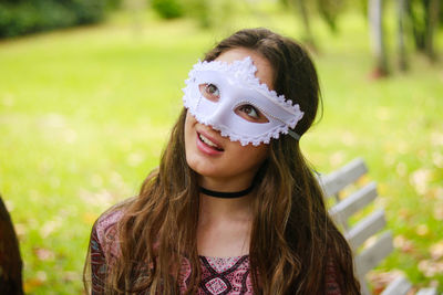 Smiling young woman wearing venetian mask at park