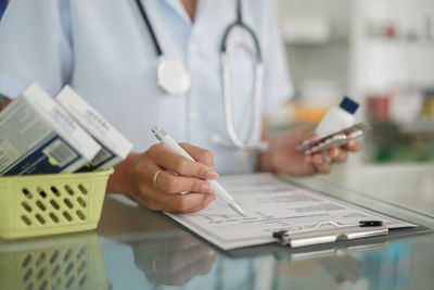 Medicine and health concept, female pharmacist hold pill bottle and capsule to writing prescription.