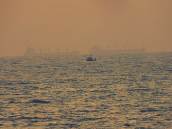 Boat sailing in calm sea at sunset