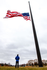 Rear view of man standing on field against sky