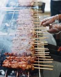 Close-up of man roasting meat on barbecue grill