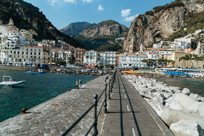 Boats moored at harbor by mountains against sky