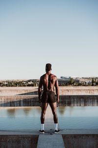 Sportsman standing on wall against clear blue sky during sunny day