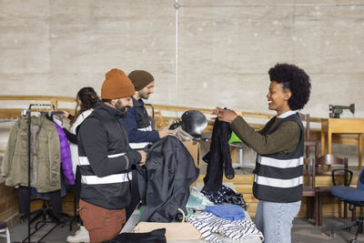 Happy male and female workers sorting recycled clothes at recycling center