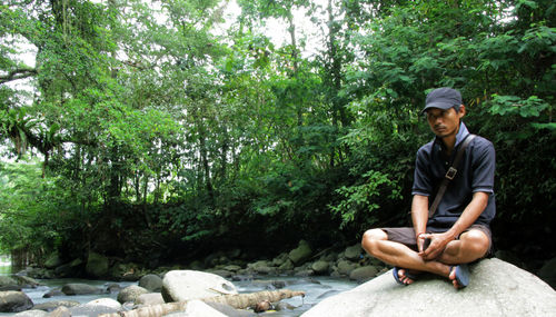 Man sitting on rock at forest