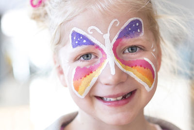 Portrait of smiling girl with painted butterfly on face