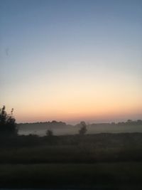 Silhouette trees on landscape against sky during sunset