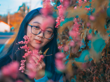 Close-up of thoughtful young woman holding pink roses outdoors