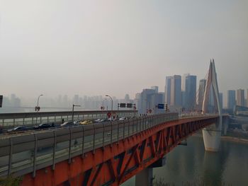 Bridge over river in city against sky