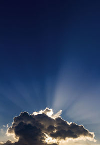 Cumulus of clouds over a mountain in backlight with the rays of the sunset sun marked in the sky