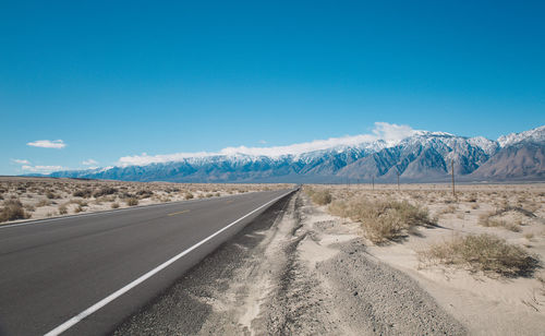 Road by mountains against clear blue sky