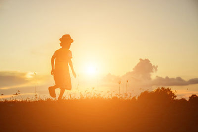 Silhouette man standing on field against sky during sunset