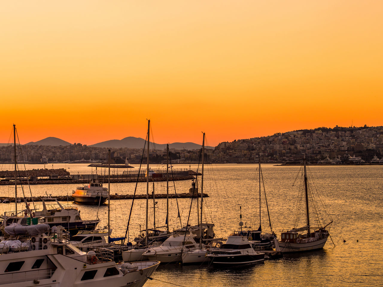 SAILBOATS MOORED IN HARBOR AT SUNSET