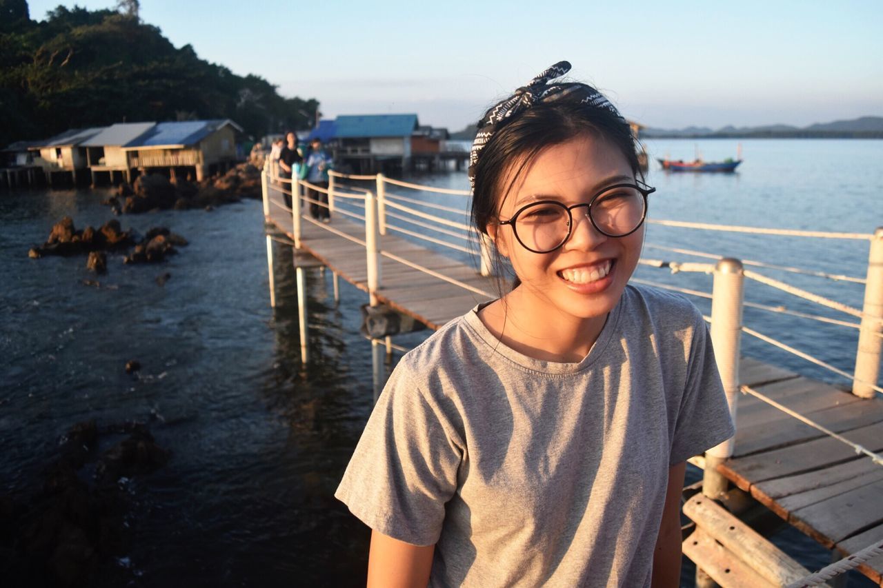 real people, one person, water, outdoors, eyeglasses, sea, standing, front view, leisure activity, day, looking at camera, lifestyles, smiling, portrait, nature, young adult, young women, beauty in nature, sky, mammal