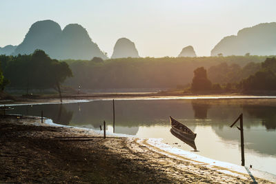 Wooden boat on nong thale lake at sunrise with karst mountain