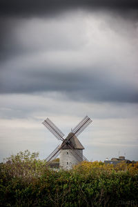 Traditional windmill on field against cloudy sky