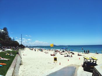 People on beach against clear blue sky