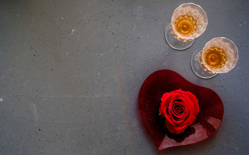 Red rose on heart-shaped plate, with two glasses of liquor nearby