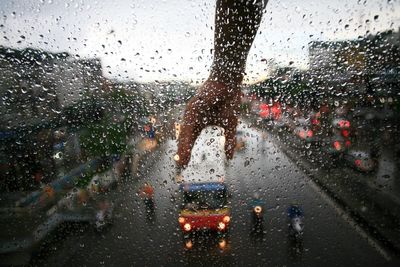 Cars on road seen through wet window in rainy season