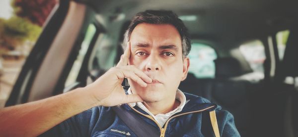 Portrait of man holding mobile phone in car