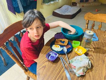 High angle portrait of girl sitting on table at home