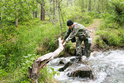 Man crossing river in forest