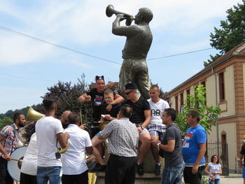 People standing by statue against sky