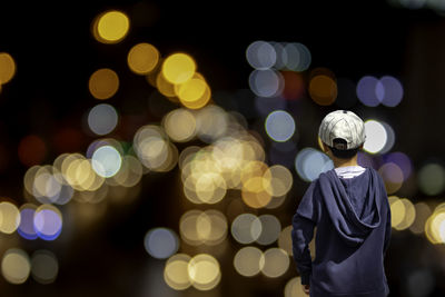 Rear view of man standing against illuminated christmas lights