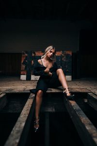 Young woman looking away while sitting on wood