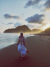 Woman on beach against sky during sunset