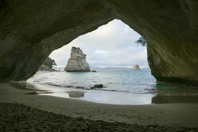 Te hoho rock seen through a rock arch at a coastal area named cathedral cove