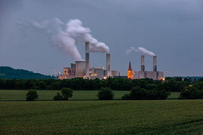 Smoke emitting from factory against sky