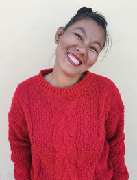 Portrait of smiling young woman against wall