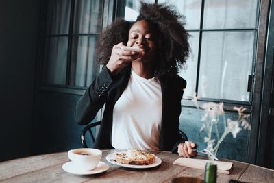 Young woman holding coffee cup on table at home